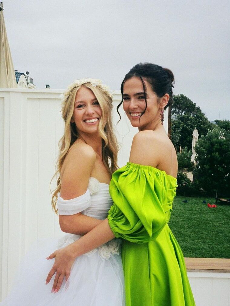 Zoey Deutch wears a lime green dress and poses with the bride. 