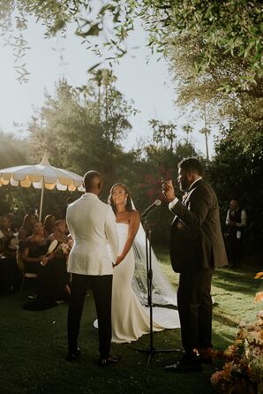 Groom in White Tux Jacket and Bride in Simple, Sleek Gown and Veil at Altar With Officiant, Colorful Umbrellas