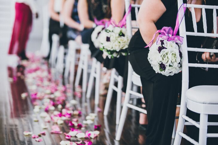 Floral pomanders hung on fuchsia ribbon to decorate the white chiavari chairs lining the aisle during the ceremony.