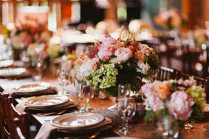 The reception decor struck the perfect balance between rustic, glamorous and romantic with wooden farm tables topped with shimmering table runners, gilded accents and full arrangements of classic garden blooms like roses, peonies, phlox, larkspur and hydrangeas. The centerpieces were arranged in footed glass vases and infused the reception tabletops with a note of femininity and elegance.