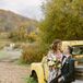 Bride in Colorful Gown, Fall Bouquet and Groom in Green Tuxedo Sitting on Truck, Rustic Setting