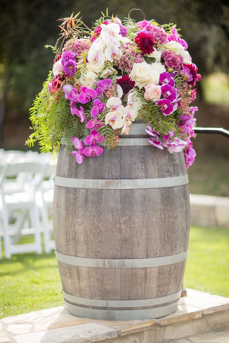 Marking the entrance to the ceremony seating area were two wine barrels topped with cascading purple orchids, ivory garden roses, passion vines and pepperberries.