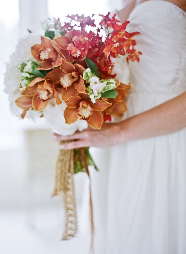 In her bridal bouquet, Tess mixed red and orange orchids for a textured feel against simple white peonies.