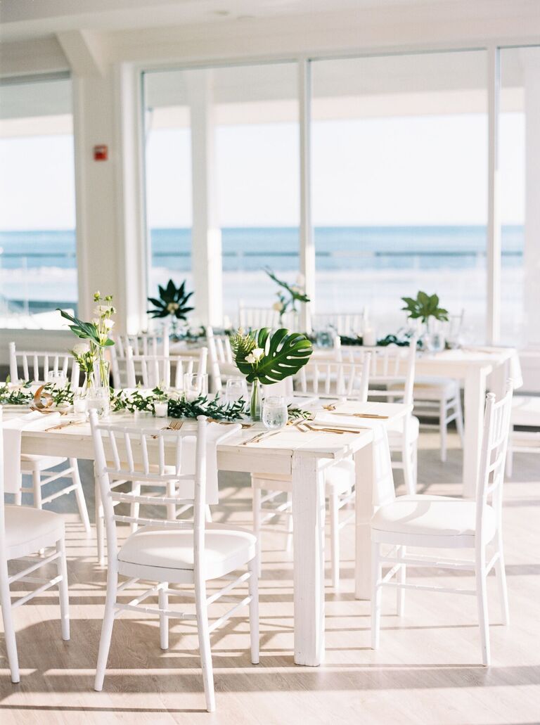 All-white reception decor with tropical leaf centerpieces