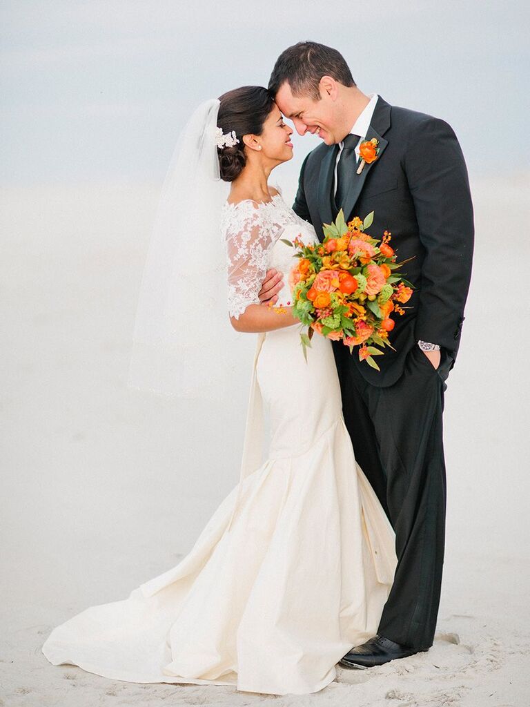 bride and groom on the beach with orange flowers