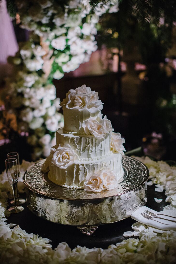 Leslie selected a rustic-meets-elegance white wedding cake with fresh flower accents. The cake had to be buttercream, as I love the strokes of the buttercream and airy quality that the frosting exudes, explains the bride. Plus, it just tastes amazing! The cake was punctuated with white flowers to enhance the romance theme and add more texture to the cake.
