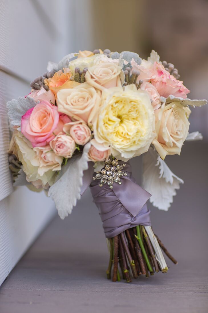 Beth's bouquet consisted of peach and pink roses, white ranunculus flowers and dusty miller. The bouquet was wrapped in purple ribbon and held together with a rhinestone brooch.
