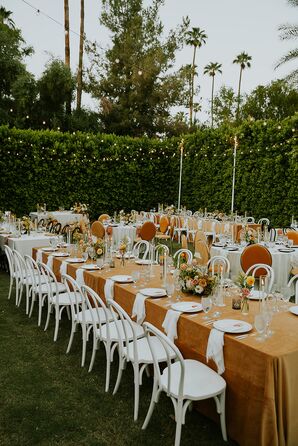 Long Tables With Orange Linens, Low Centerpieces and Candles on Lawn Under String Lights