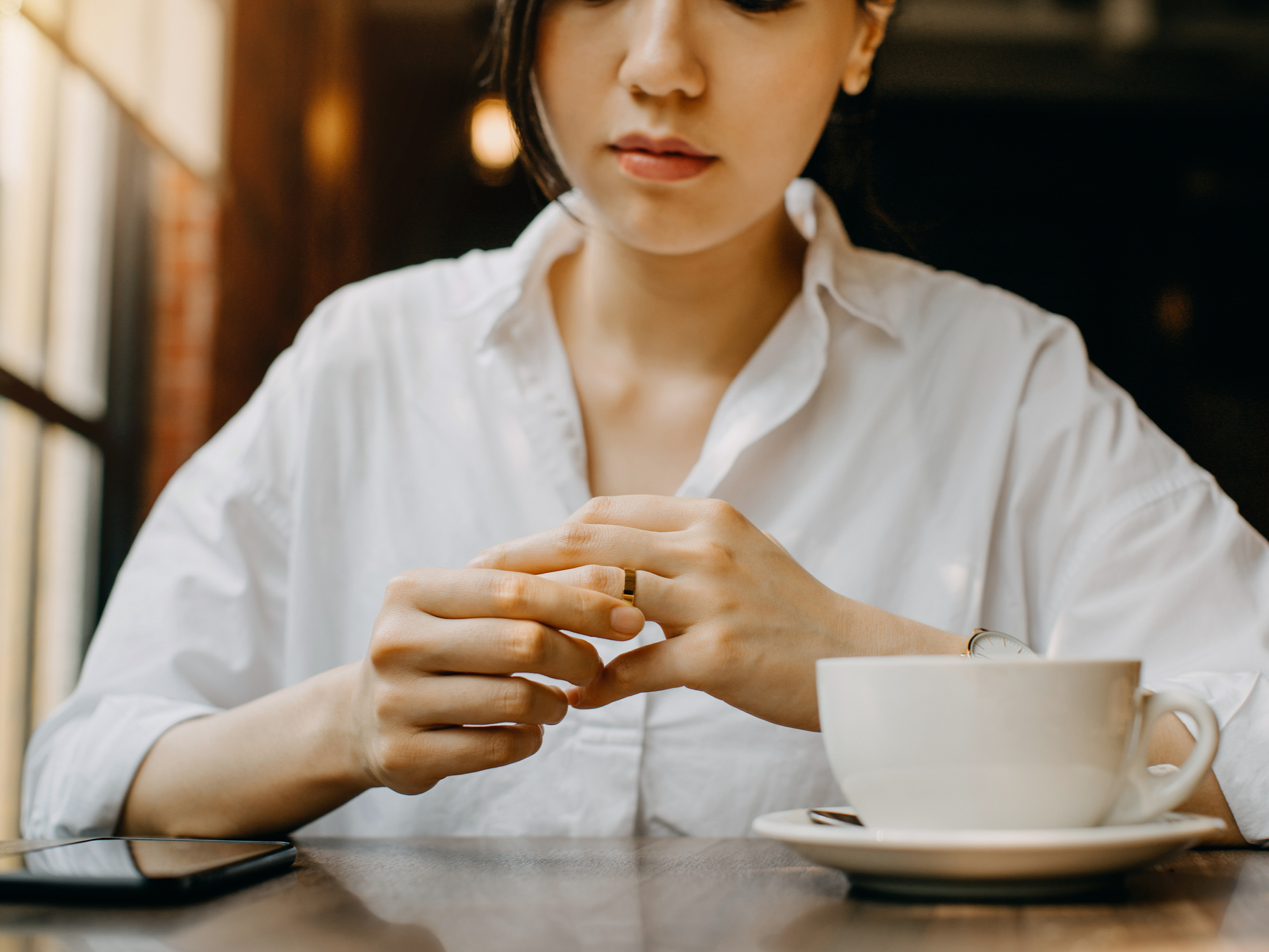 Woman thinking while holding wedding ring