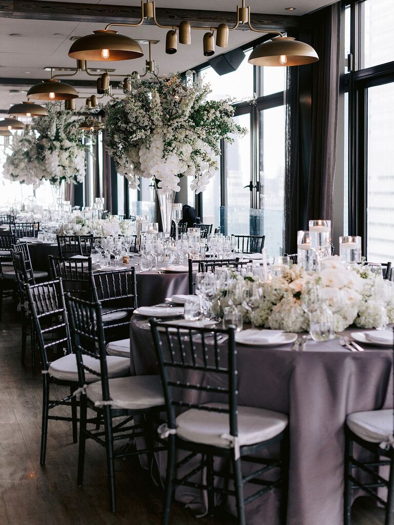 indoor wedding reception with high and low white centerpieces on round tables