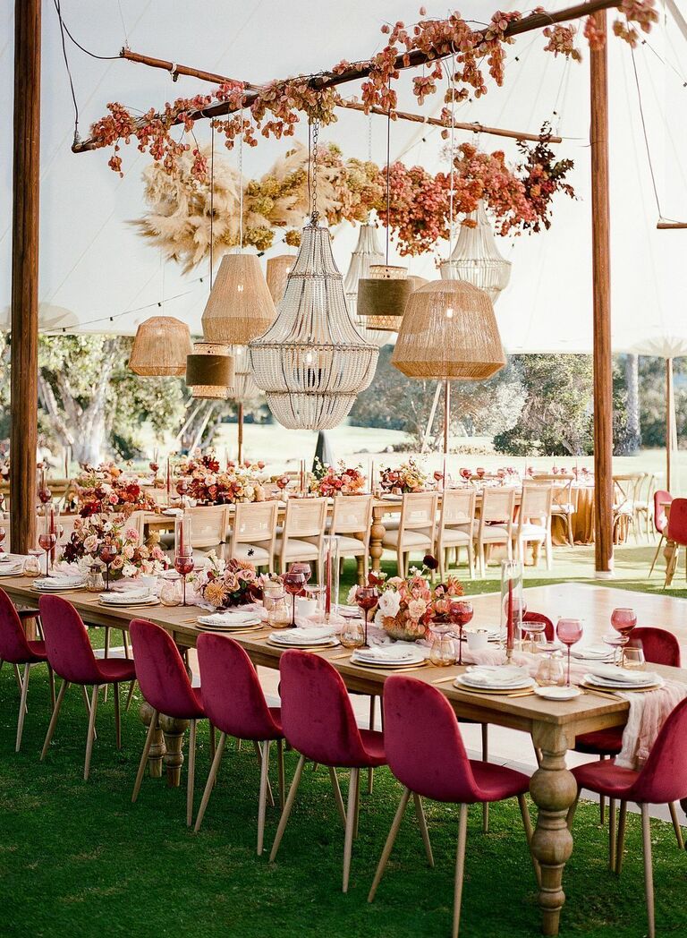 Tented reception with mismatched chandeliers and burgundy velvet chairs