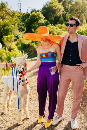 Couple in Orange Outfits Posing With Alpaca