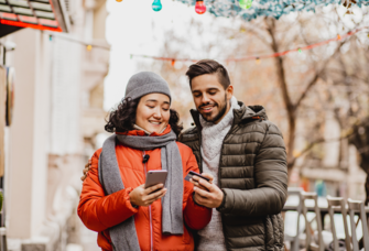 Couple on phones while talking walk outside during the winter