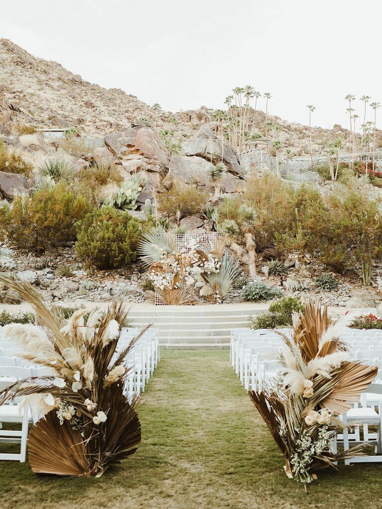 Outdoor bohemian wedding ceremony at desert venue with pressed palms and greenery