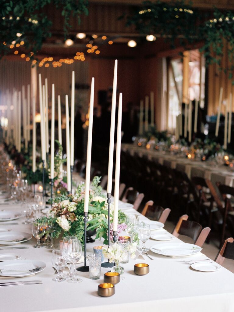 rustic wedding centerpiece with extra-tall white taper candles in bronze candle holders