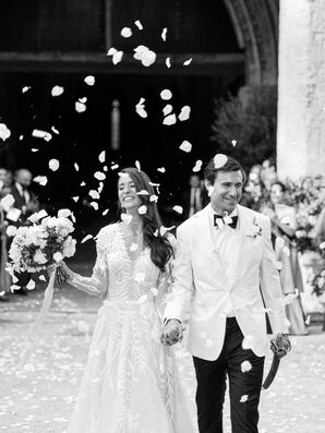 Black-and-White Photo of Couple Recessional Leaving Historic Venue, Throwing Rose Petals