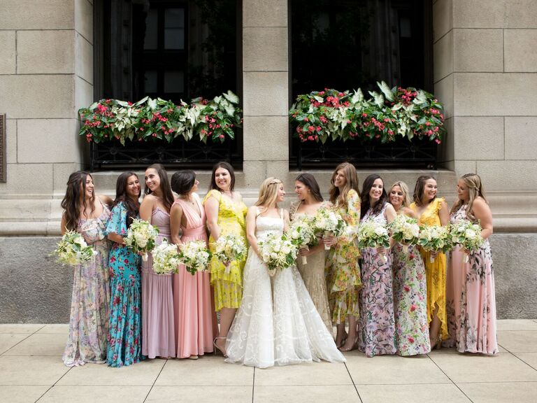 Bridesmaids wear floral print gowns in various colors. 