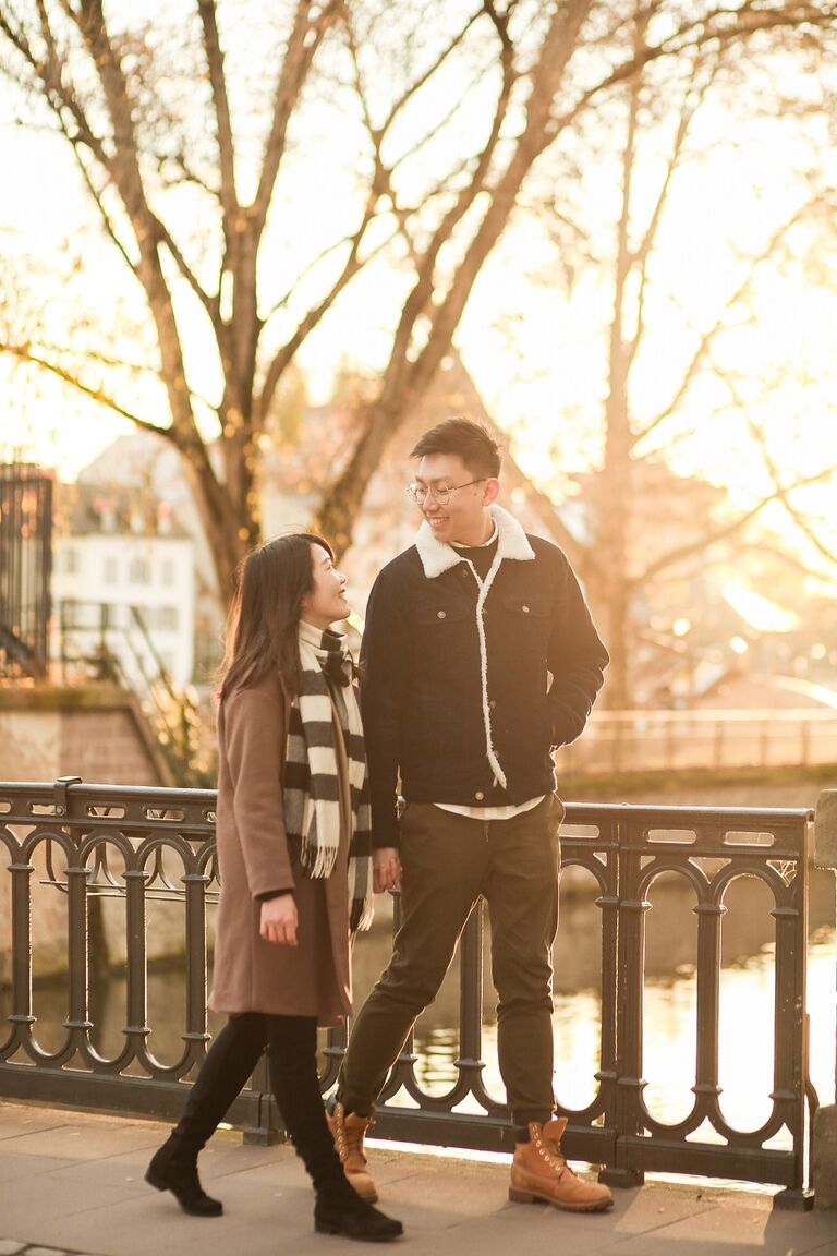 Couple walking across bridge holding hands during sunset