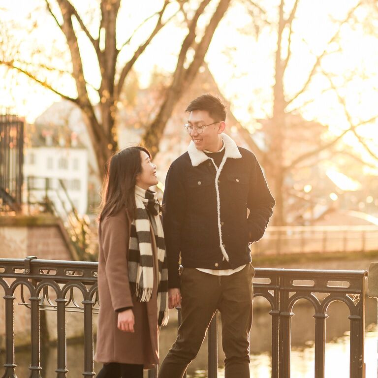 Couple walking across bridge holding hands during sunset