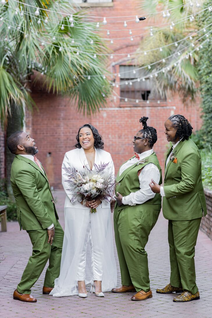 Bride in White Blazer, Pants and Bouquet With Wedding Party in Green Suits