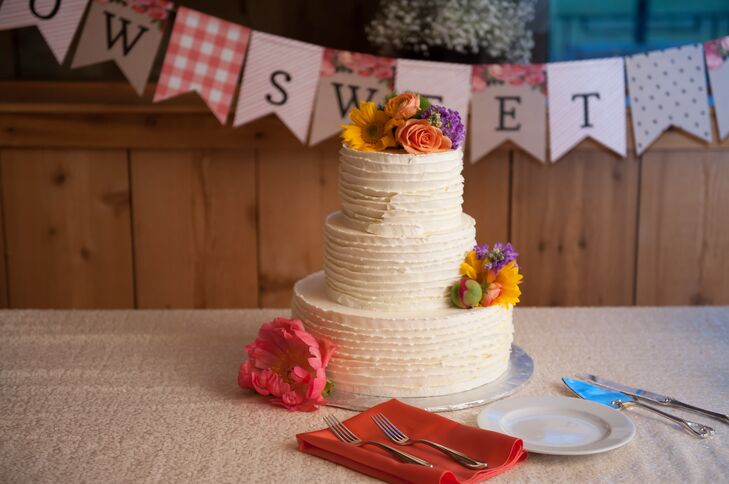 Katie and Haydn enjoyed a three-tier white ruffled buttercream wedding cake topped with fresh daisies and roses.
