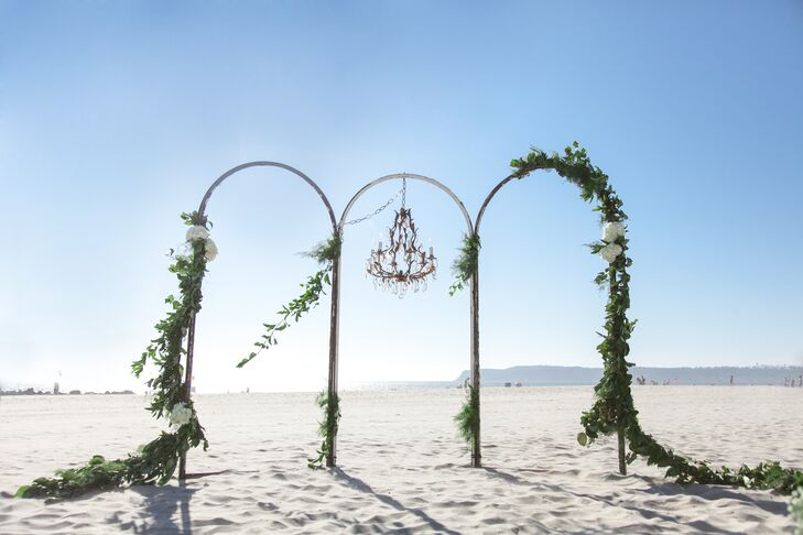 "The altar was a brass frame that my planner found. and it was asymmetrically draped with greenery with a vintage chandelier hung in the middle," Bayley says.