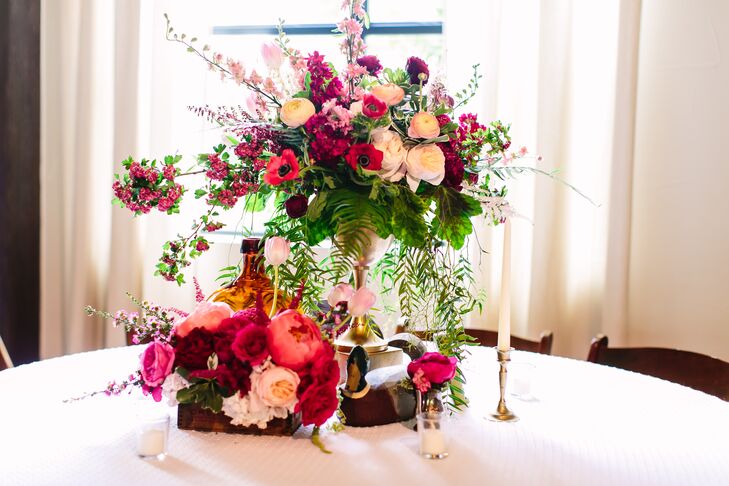 Round guest tables had textured white linens topped with overflowing flower boxes and tall vases filled with whimsical blooms. The bold and bright arrangements included garden roses, anemones, ranunculus, peonies and astilbes. Eclectic vintage decor and a host of candles surrounded the floral centerpieces.
