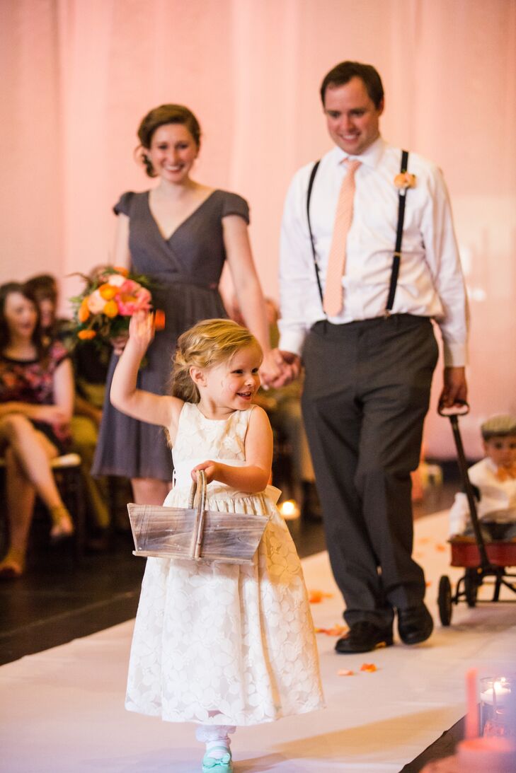 The flower girl, Effie, walked down the aisle wearing a super-cute white dress. She carried a wooden basket filled with pink and orange rose petals, which she threw as she walked down the aisle.