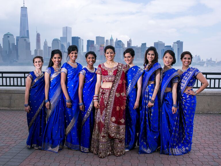 Bridesmaids wearing royal blue wedding saris while the bride wears a red lehenga. 