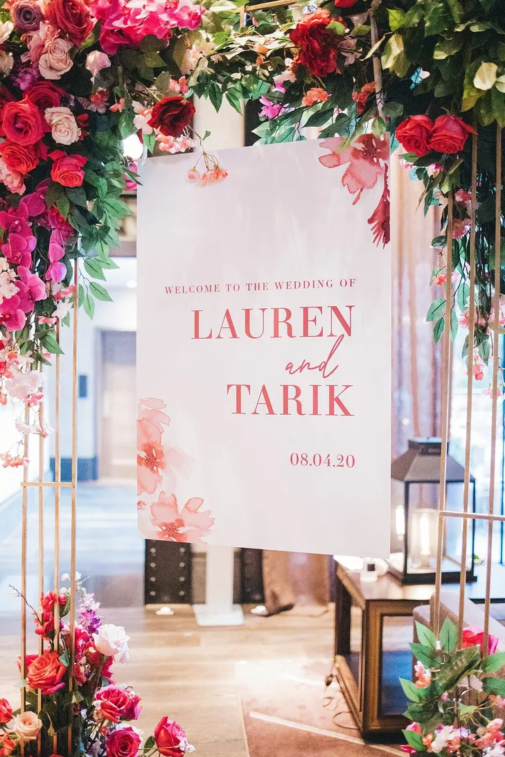Pink-and-white acrylic sign surrounded by pink roses