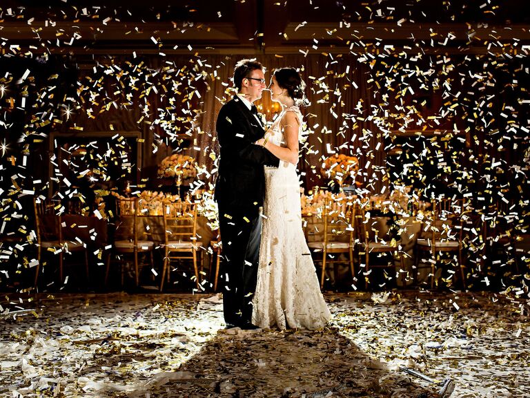 bride and groom standing in the middle of the dance floor with white and gold confetti falling around them