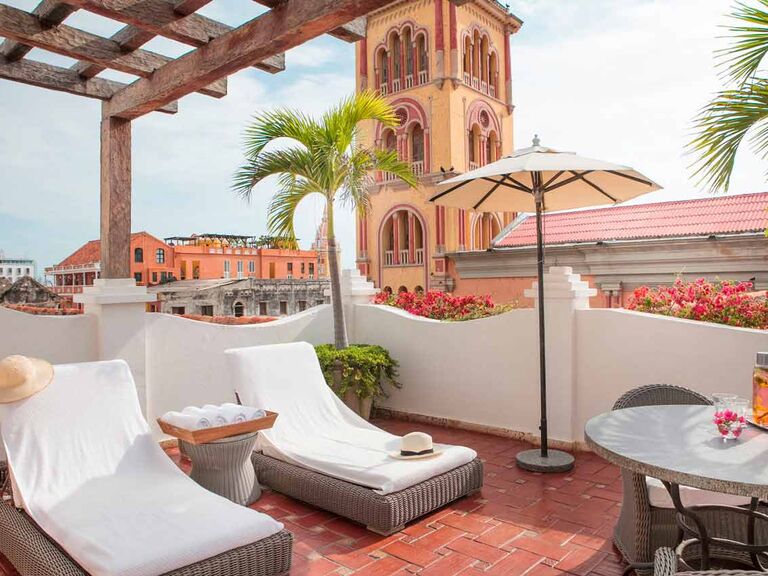 View from the hotel deck featuring lounge chairs, palm trees, and views of the colorful buildings of downtown Cartagena. 