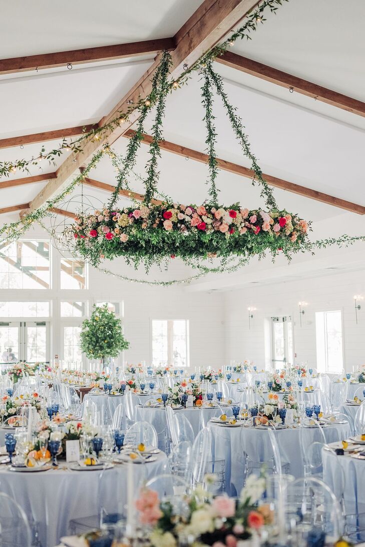 Hanging Floral Installation of Pink Flowers Over Round Tables With Blue Linens
