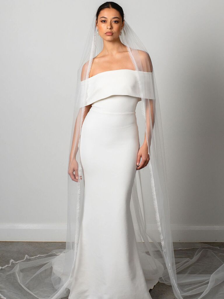 Model wears an off the shoulder white wedding dress. 