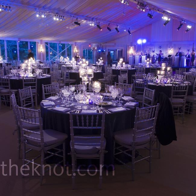 The tent was uplit with purple and blue lighting for a cool, romantic look, while minimalist centerpieces with floating candles (no flowers) topped the tables.