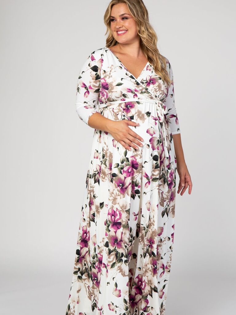 Model wears white floral maternity dress with long sleeves. 