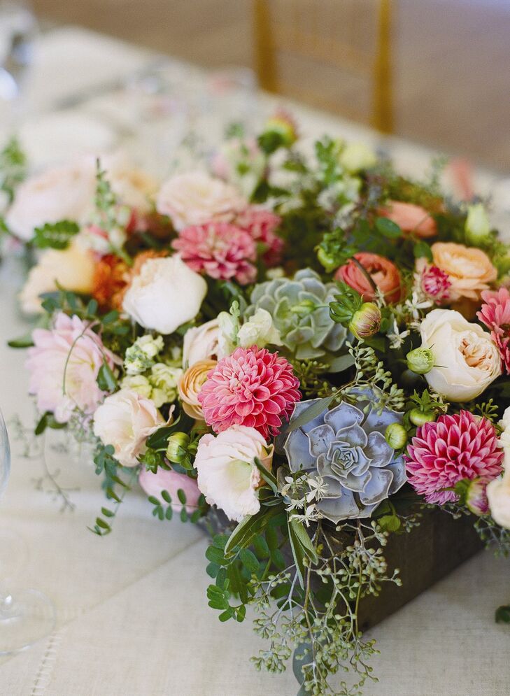 Dahlias, garden roses, ranunculus and succulents were placed inside wooden boxes on the guest tables.