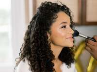 Bride gets her makeup done on her wedding day. 