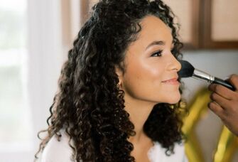 Bride gets her makeup done on her wedding day. 