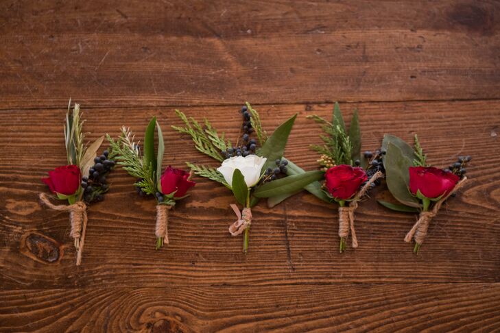 The groomsmen sported burgundy flowers with wintery navy pivot berries, while the groom wore a white rose paired with the same berries. The boutonnieres were all wrapped in natural brown twine.