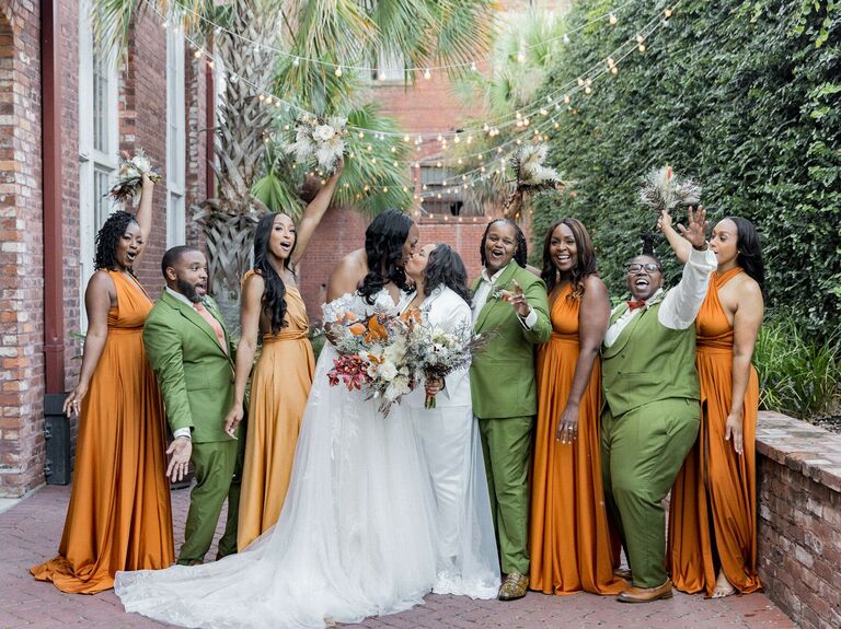 The wedding party wears alternating orange dresses and green suits. 