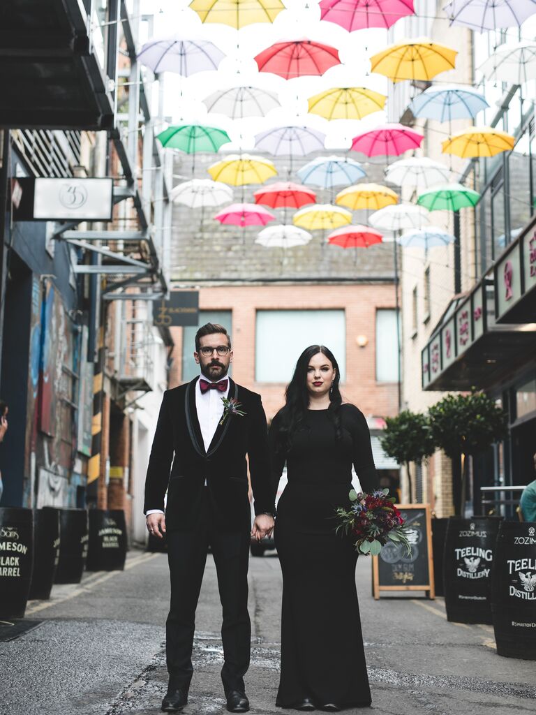 Couple holding hands in front of umbrellas