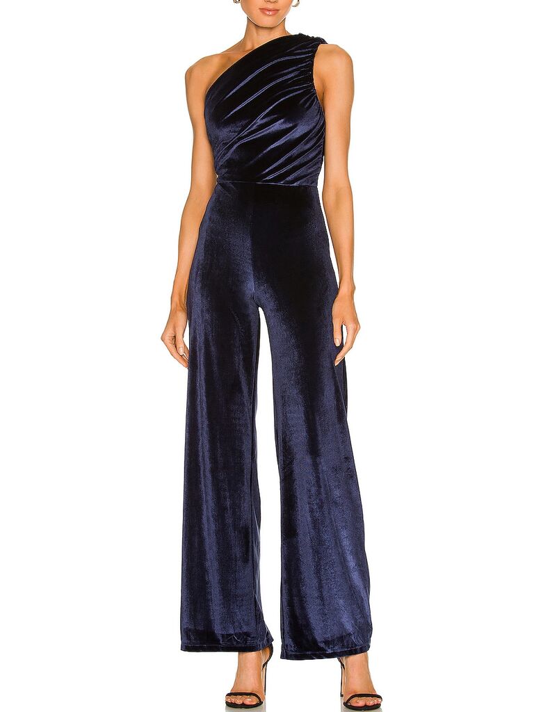 Model wearing one-shoulder velvet jumpsuit in navy blue