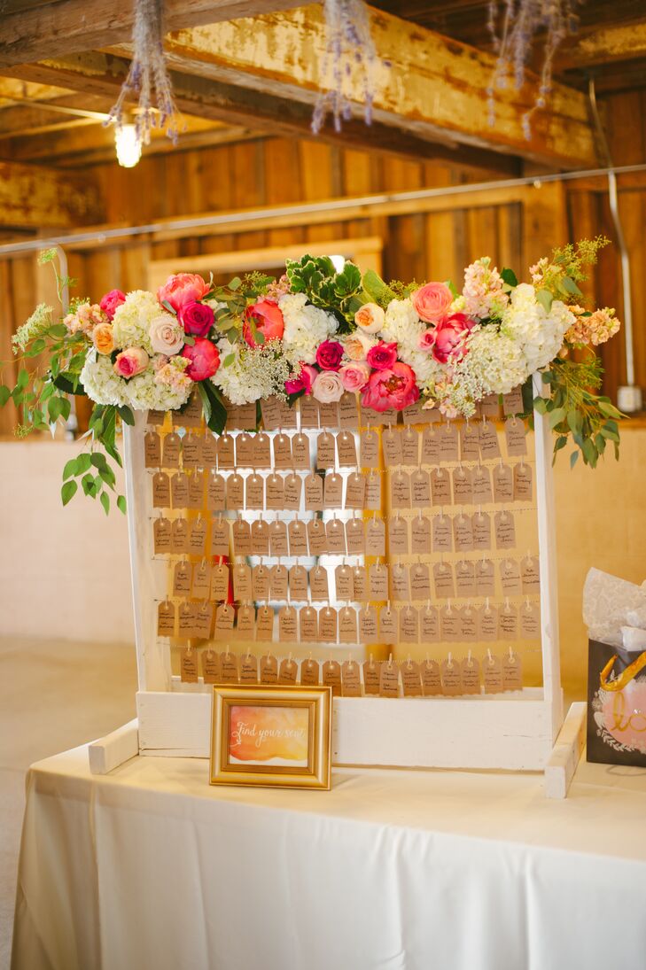 Brian built a white frame for guests to find their kraft paper escort cards, dangling on pieces of string. A pink and white lush flower arrangement filled with peonies, hydrangeas, ranunculus and more decorated the top, incorporating the garden vibe into the display's overall look.