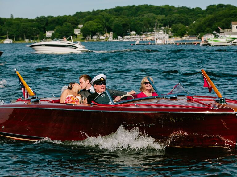 Bride and groom riding in a red boat for their reception entrance.