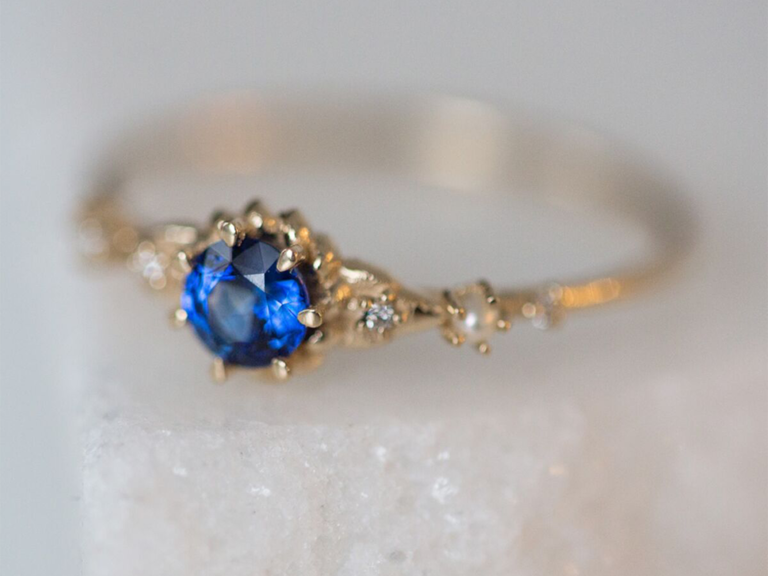 Round sapphire center stone on gold band with encrusted with diamonds