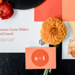 Bright terracotta and salmon themed wedding invitations surrounded by flowers