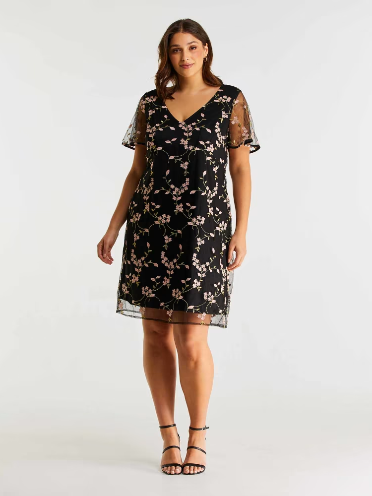 A model wears this knee-length black gown with a floral overlay.