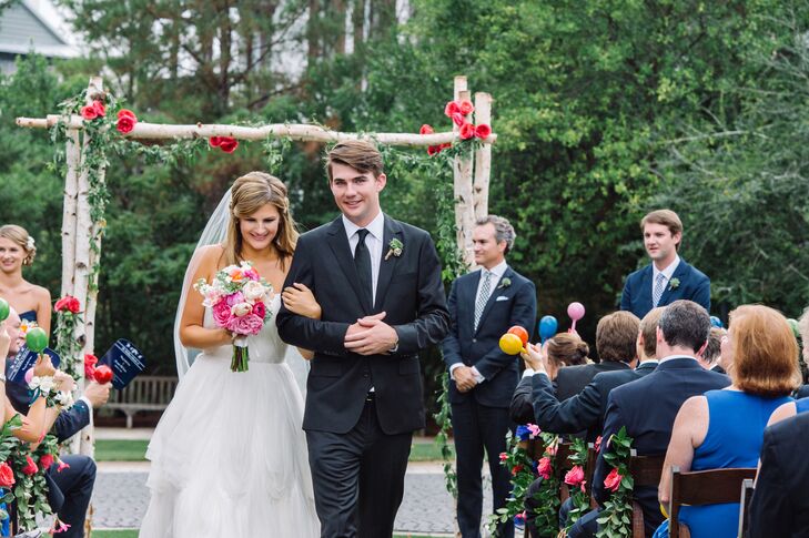 For her dress, Caroline picked a more formal,  modern look. The Watters gown had ruching along its strapless sweetheart neckline and an organza overlay that extended into a romantic, frothy skirt. A scalloped detail also fell just above her knee.