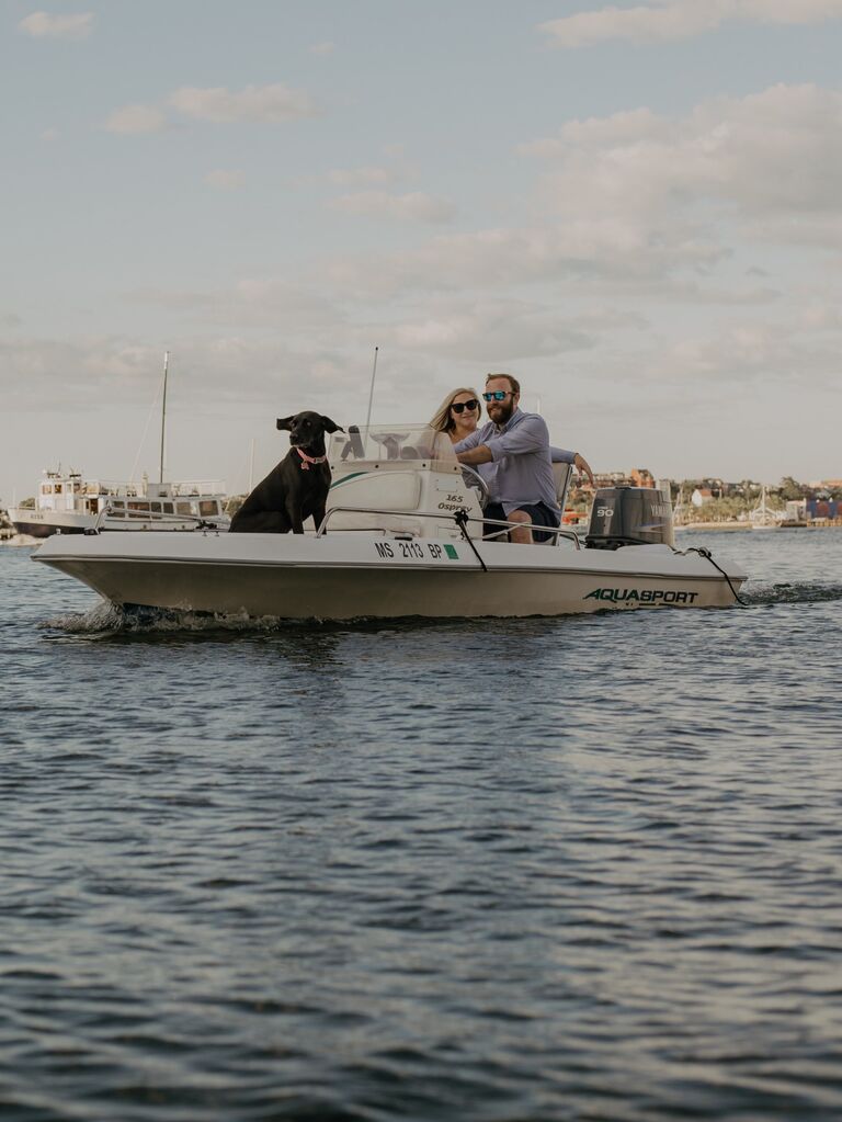 Couple pose on their boat with their dog. 